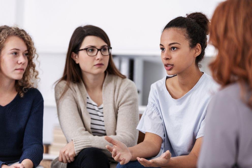 Frauen sitzen nebeneinander und sind im Gespräch