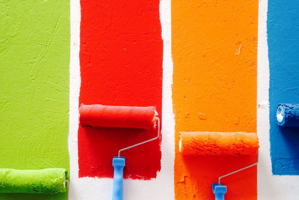Bunte Farbroller streichen eine Wand in verschiedenen Farben.