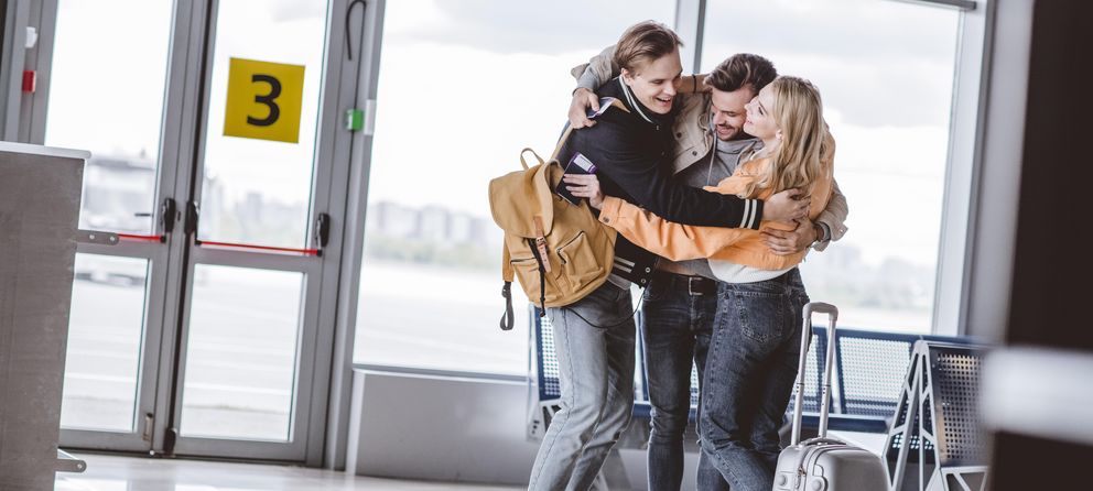 Junge Menschen begrueßen Freund an Flughafen