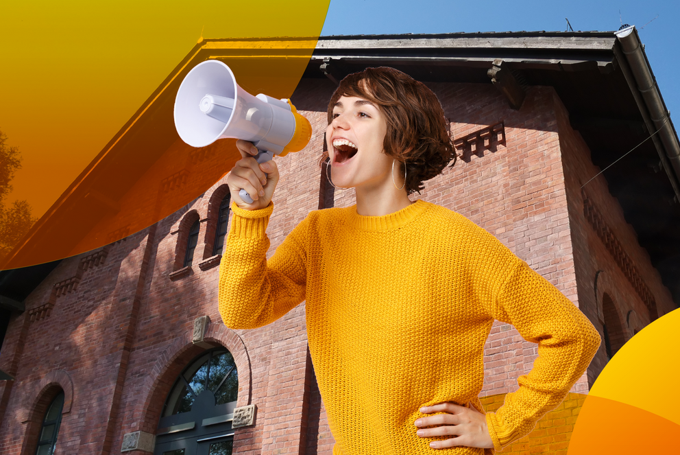 A student with a megaphone in front of the Innsteg Auditorium